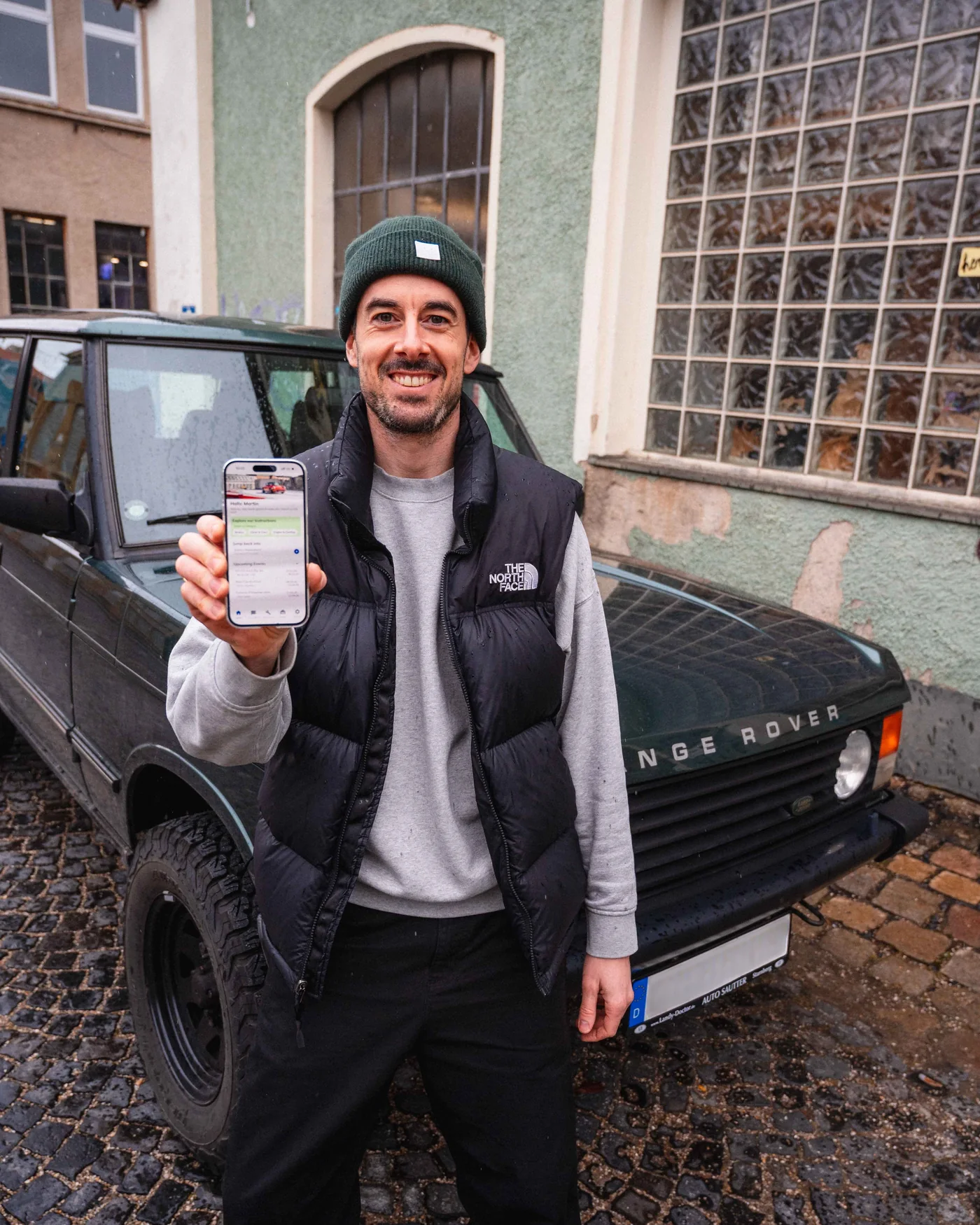 Martin Rothacher, Gründer von MINT Product Studio, mit der MINT Instructions App vor einem klassischen Range Rover in München